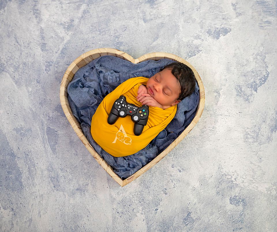 Heart-shaped prop filled with blue fabric and gaming controller design for newborn photography.