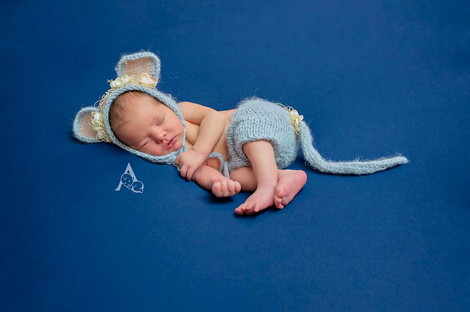 Newborn wearing mouse ears and tail costume on blue background.