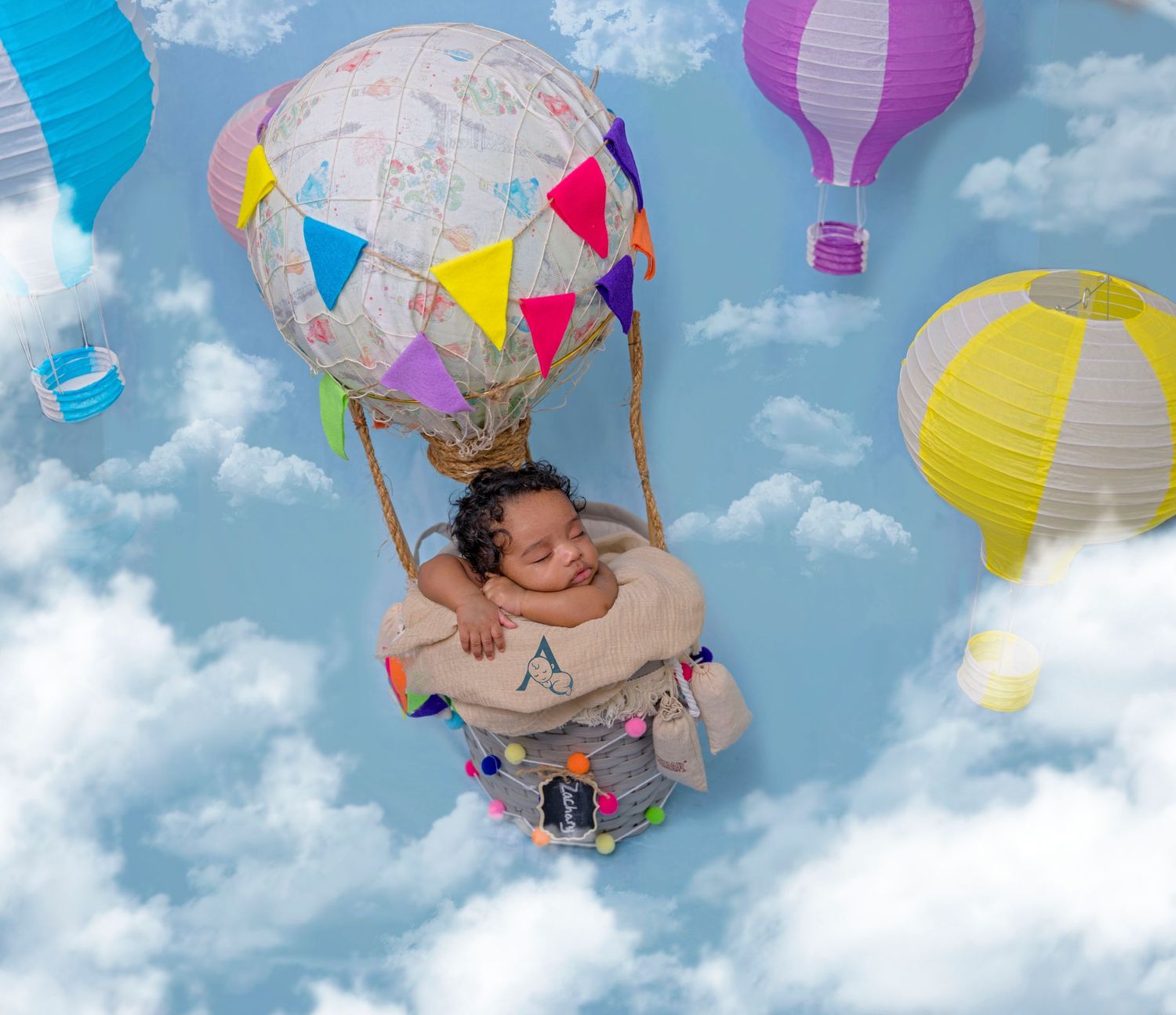 Creative baby photo with hot air balloon theme and colorful paper lanterns.