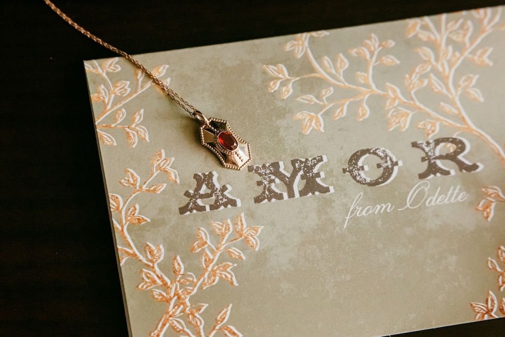 fine jewelry gold necklace with a Power pendant on top of a vintage letter that says Amor