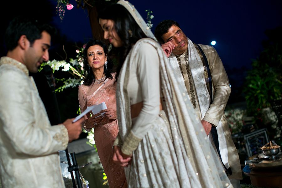 A nighttime celebration shows people in traditional white outfits during a wedding ceremony.