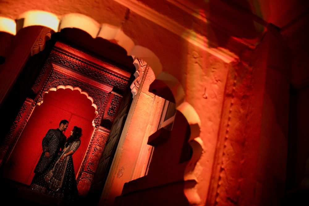 A romantic silhouette of a couple is framed by ornate red-lit archways in traditional architecture.