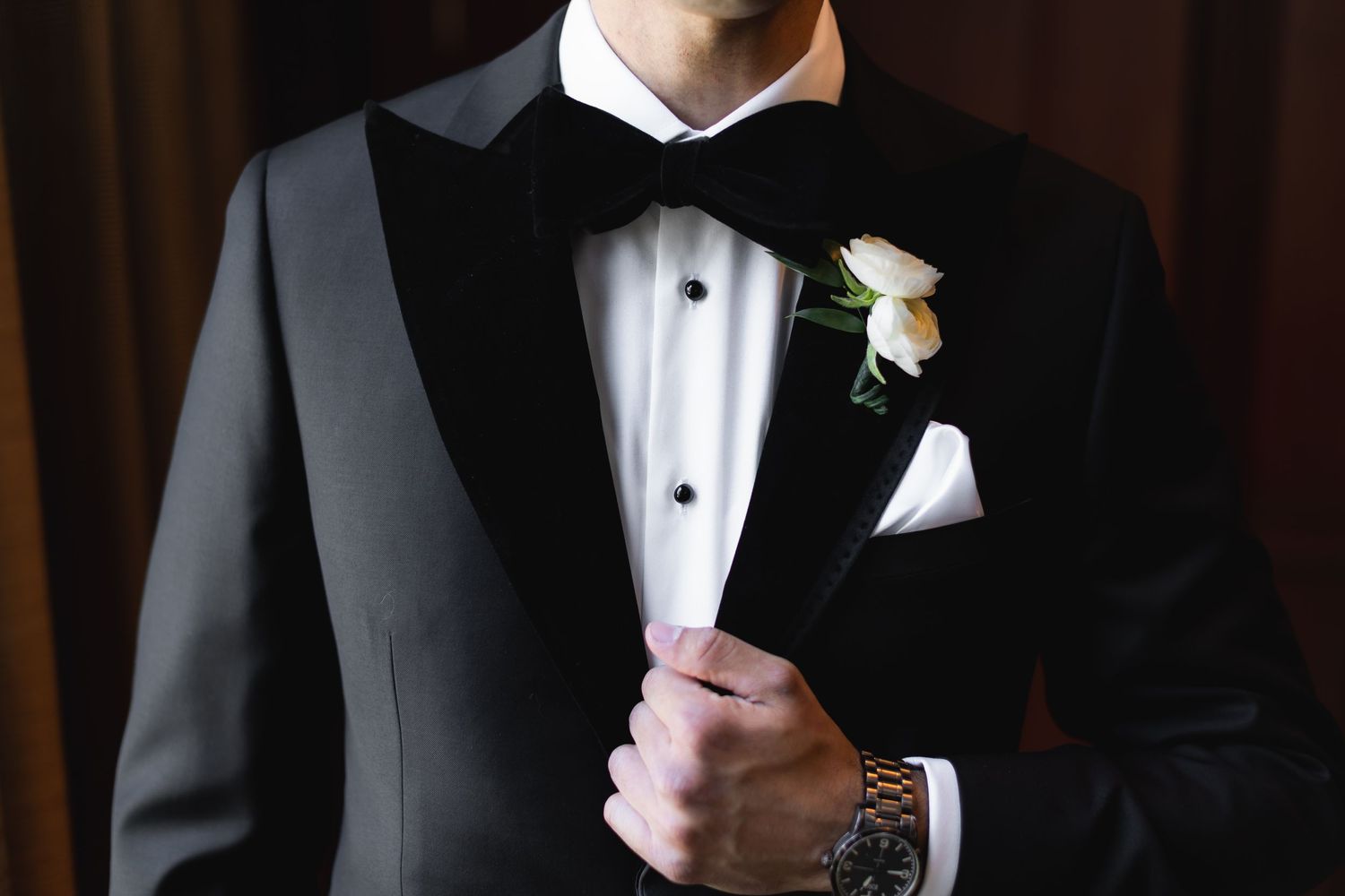 Close-up details of tuxedos and boutonnières at a formal event.