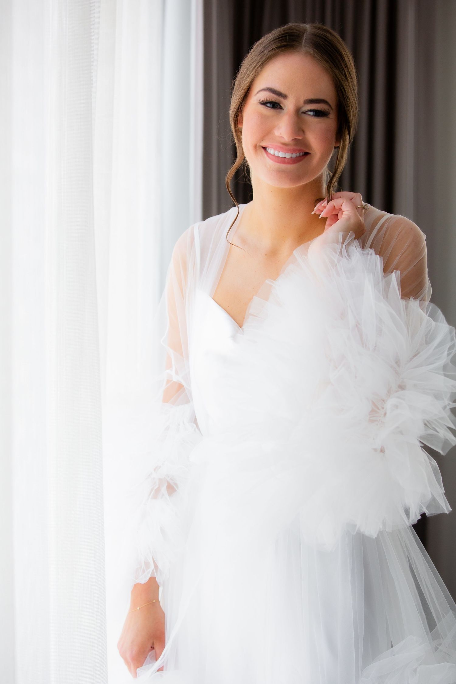 Elegant bridal portraits featuring white tulle gown details near window.