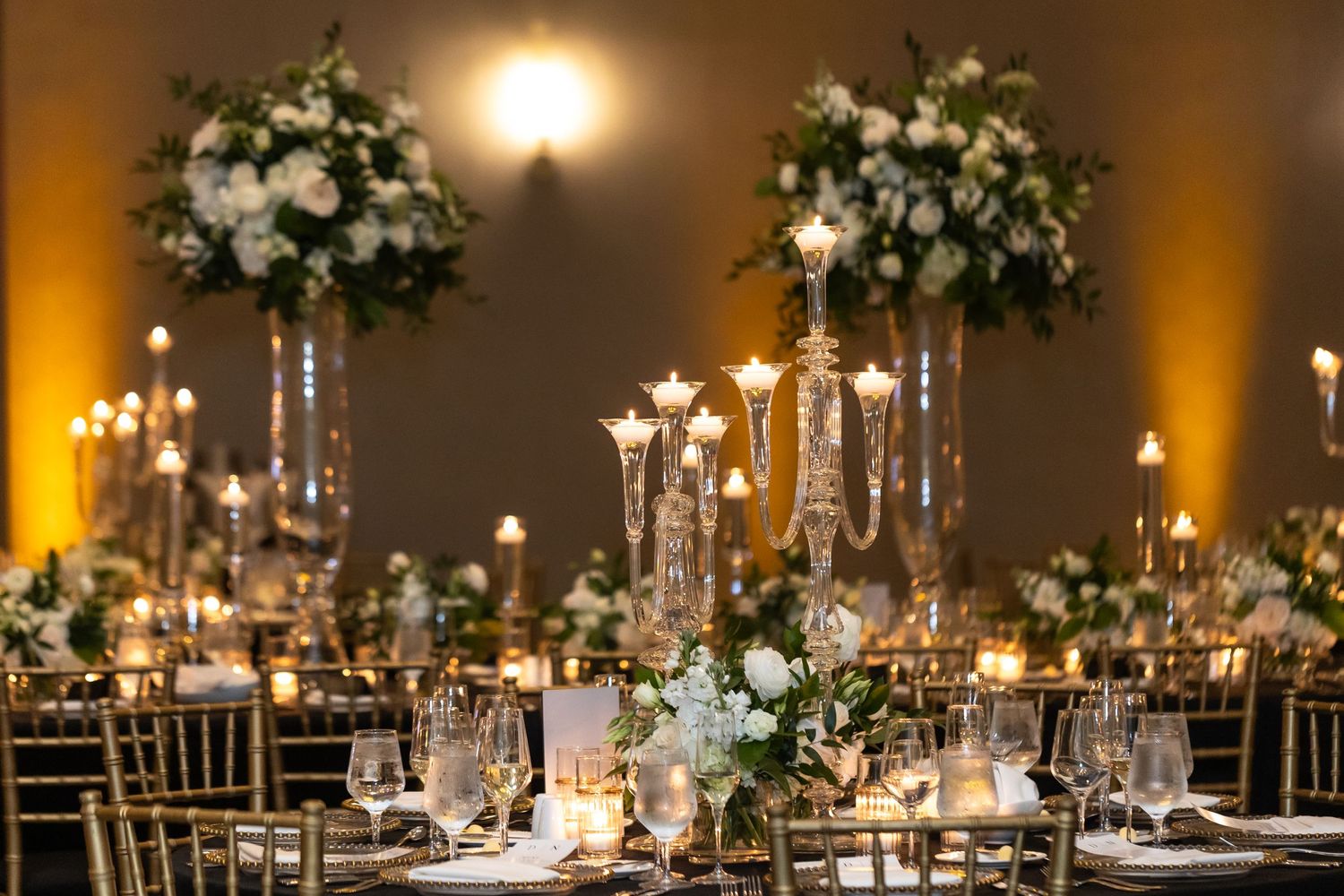 Long banquet tables decorated with white floral centerpieces and elegant candle arrangements.