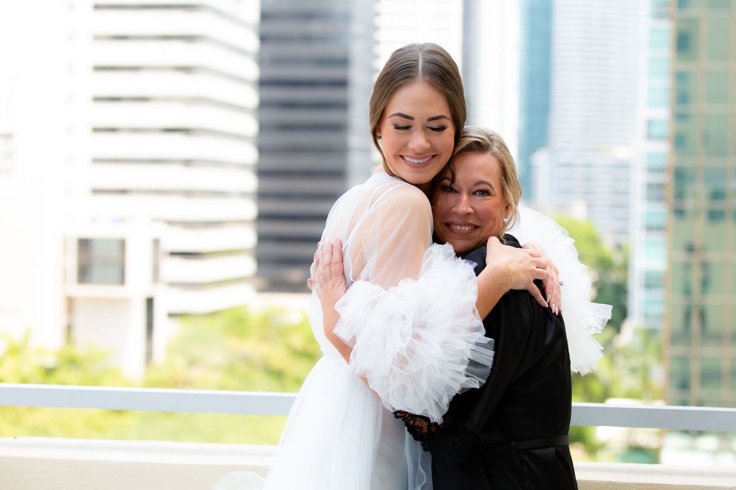 Emotional embrace captured during a wedding photoshoot on a rooftop terrace with city views.