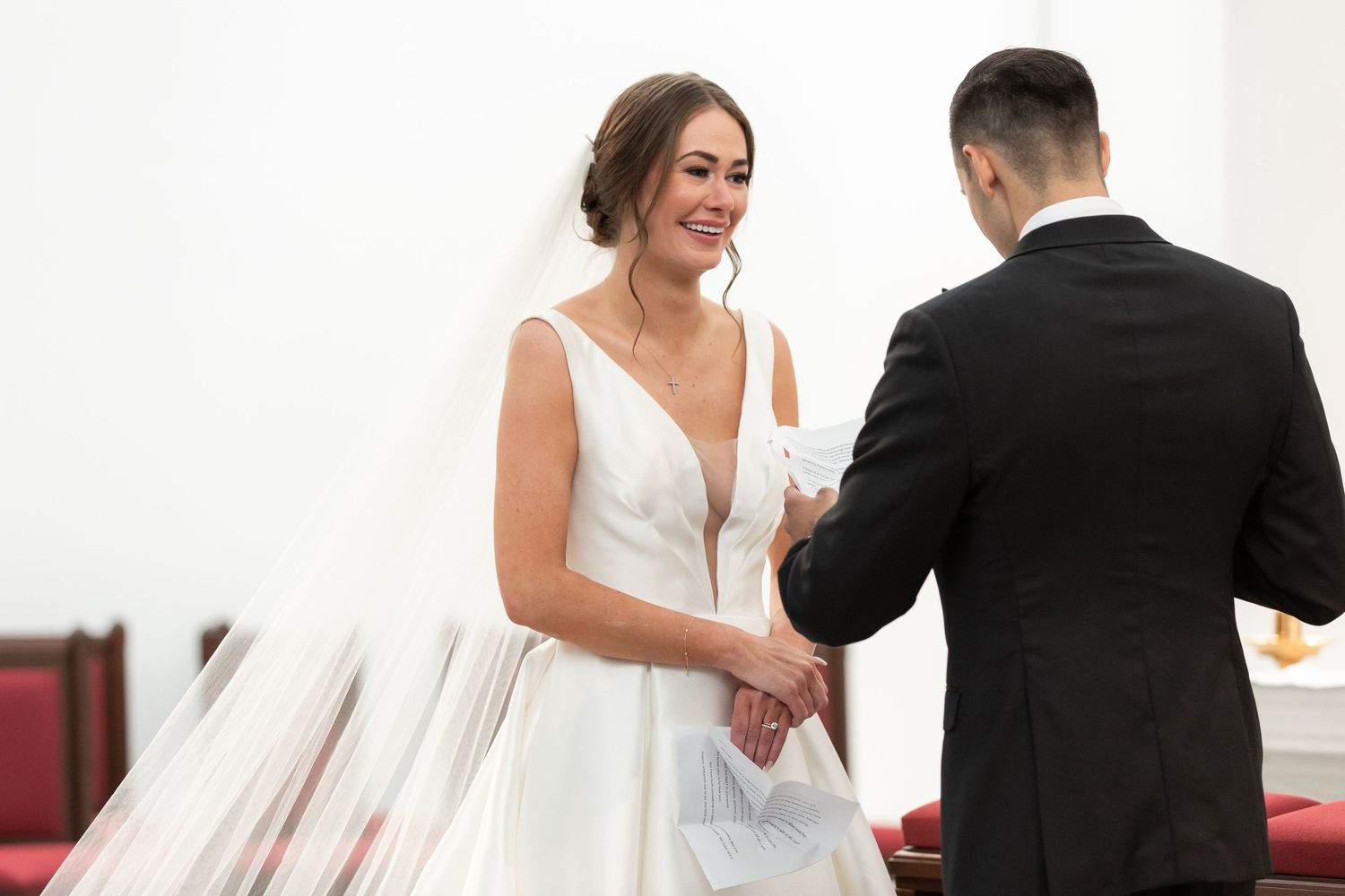 A couple raises a toast together during their wedding ceremony in a bright modern church setting.