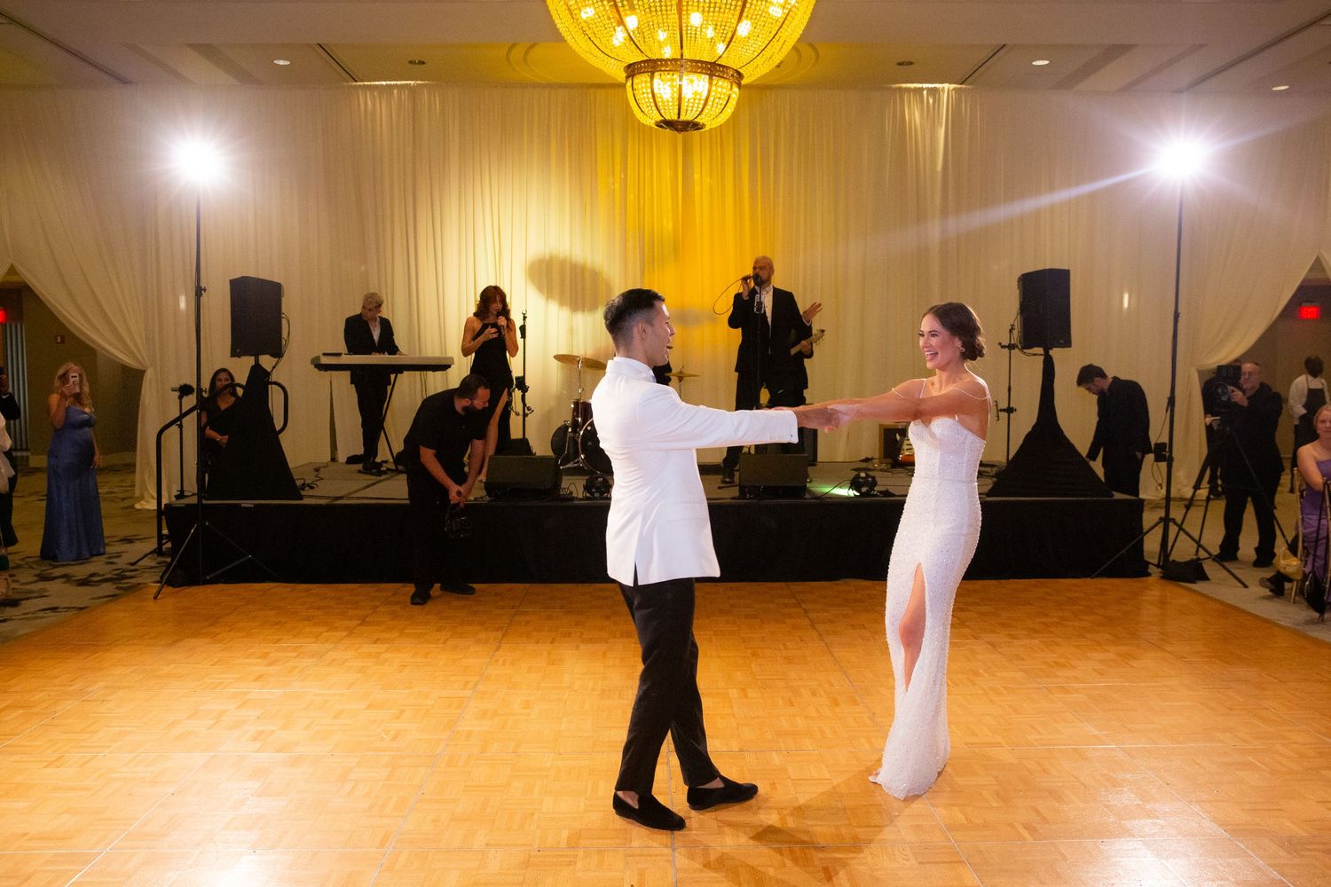 Wedding guests dance in a warmly lit ballroom during the reception celebration.
