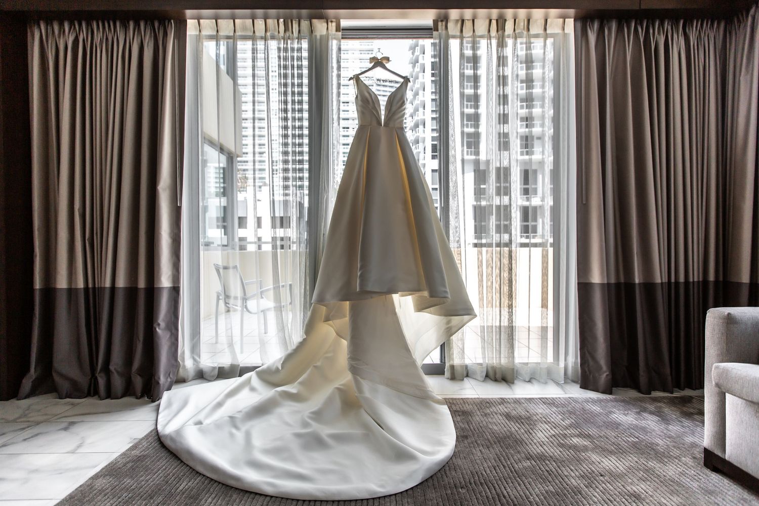 Modern hotel room interior with floor-to-ceiling windows and dark curtains.