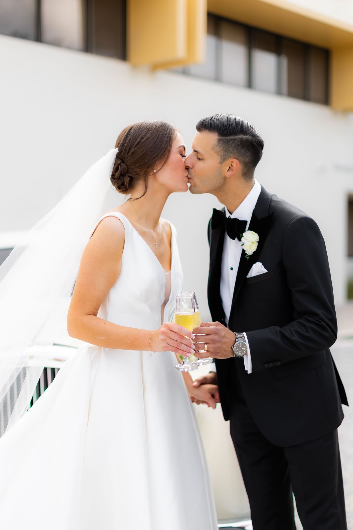 Romantic moment between newlyweds sharing champagne outdoors.