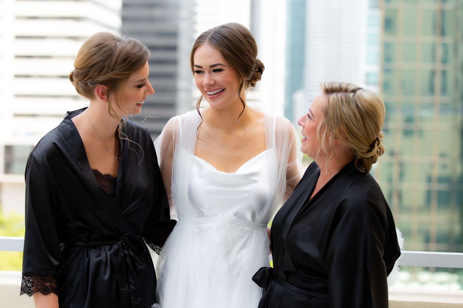 Wedding party members share laughs and hugs during a rooftop photo session.