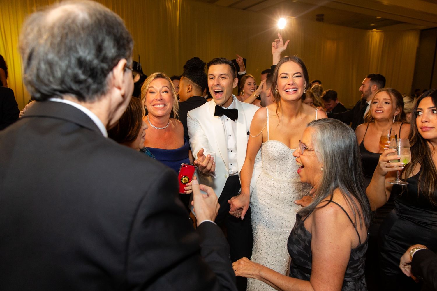 Wedding guests dancing and celebrating on a parquet floor at an elegant reception venue.