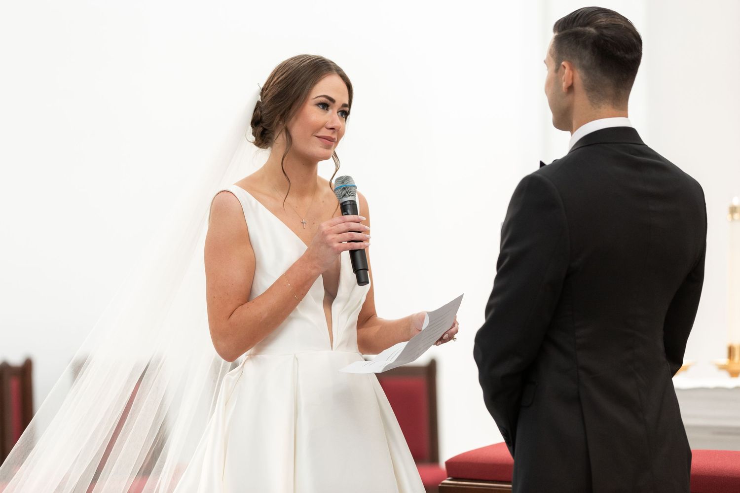 A bride and groom share a drink moment during their wedding ceremony in a bright interior.