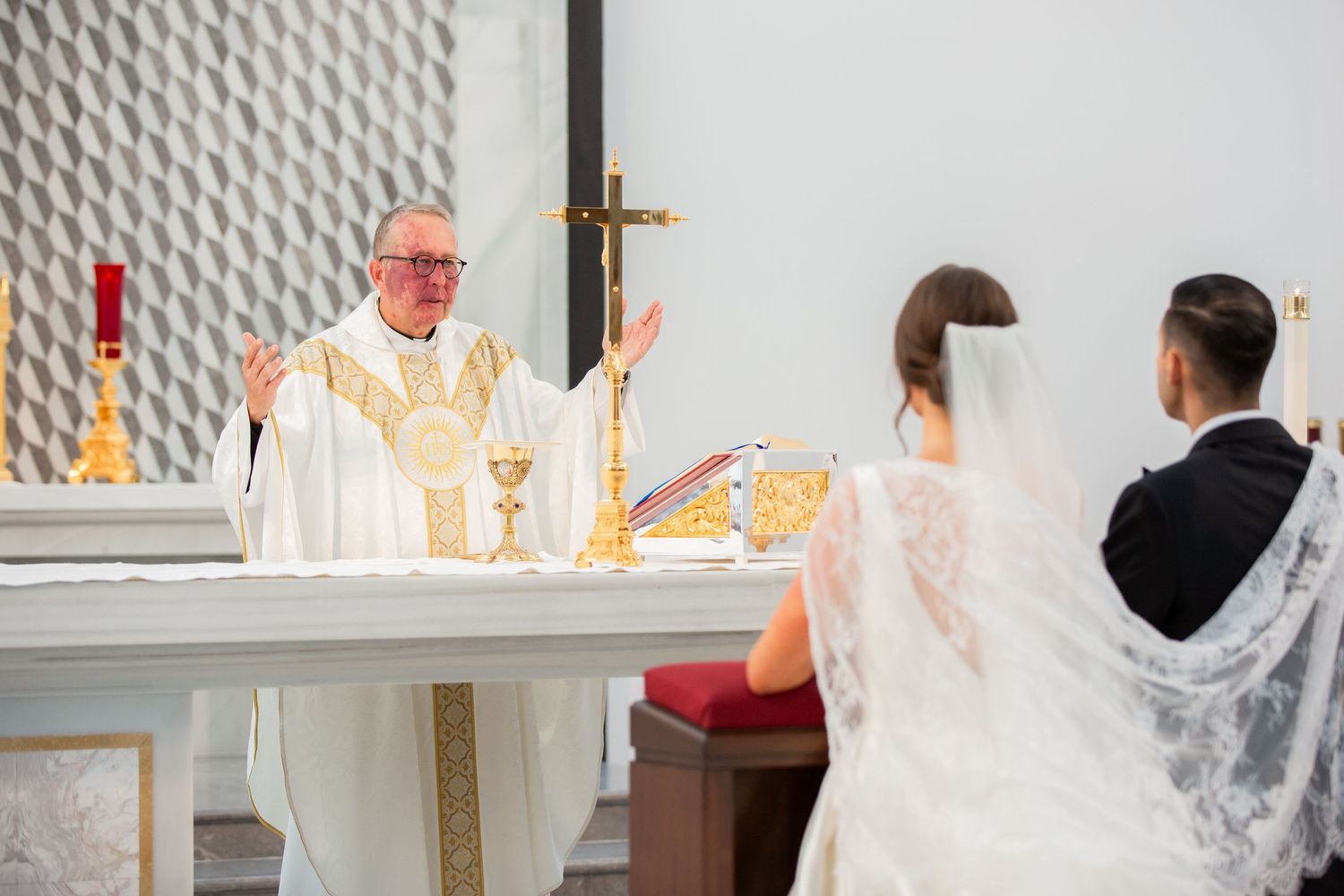 Wedding ceremony with distinctive honeycomb pattern wall and altar candles.
