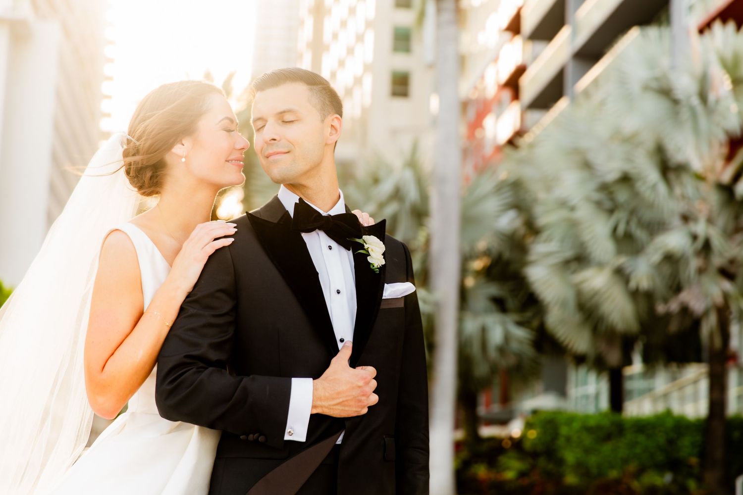 Joyful wedding moment captured against modern architecture and palm trees.