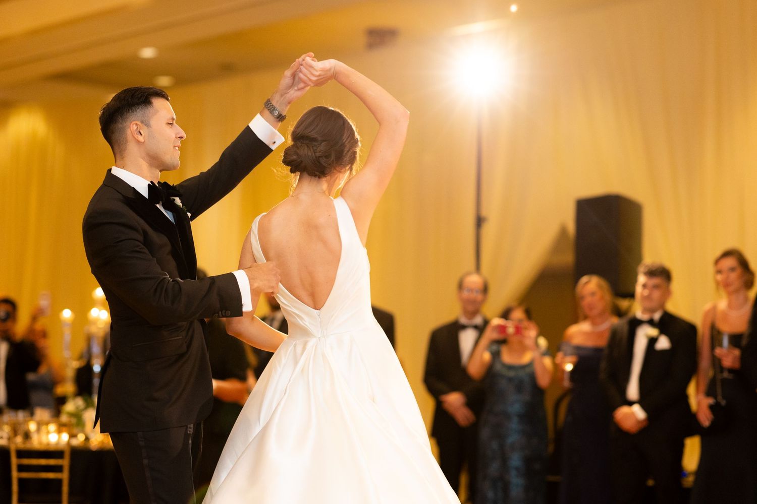 An elegant dance move during a wedding first dance with warm golden lighting.