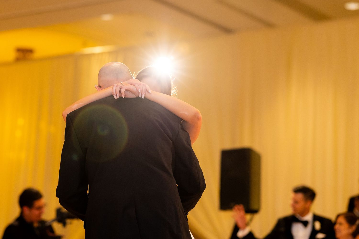 Wedding celebration in a grandly lit ballroom with couples dancing together.