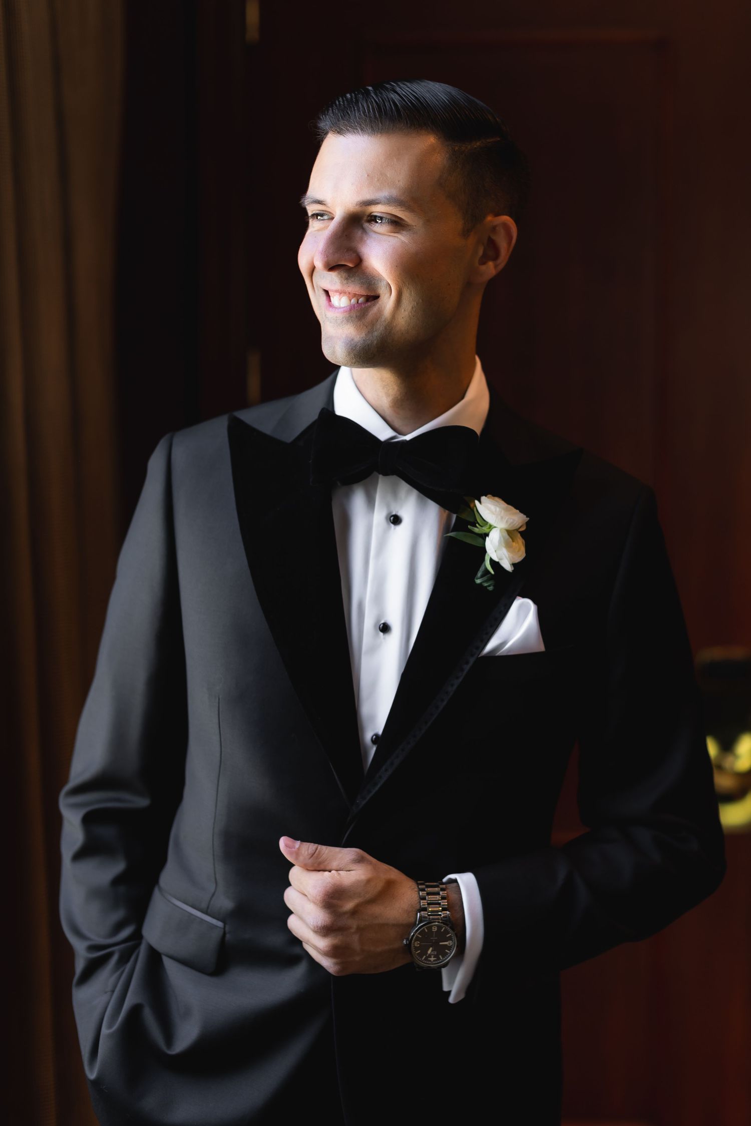 Wedding party members in classic tuxedos photographed in dramatic lighting.