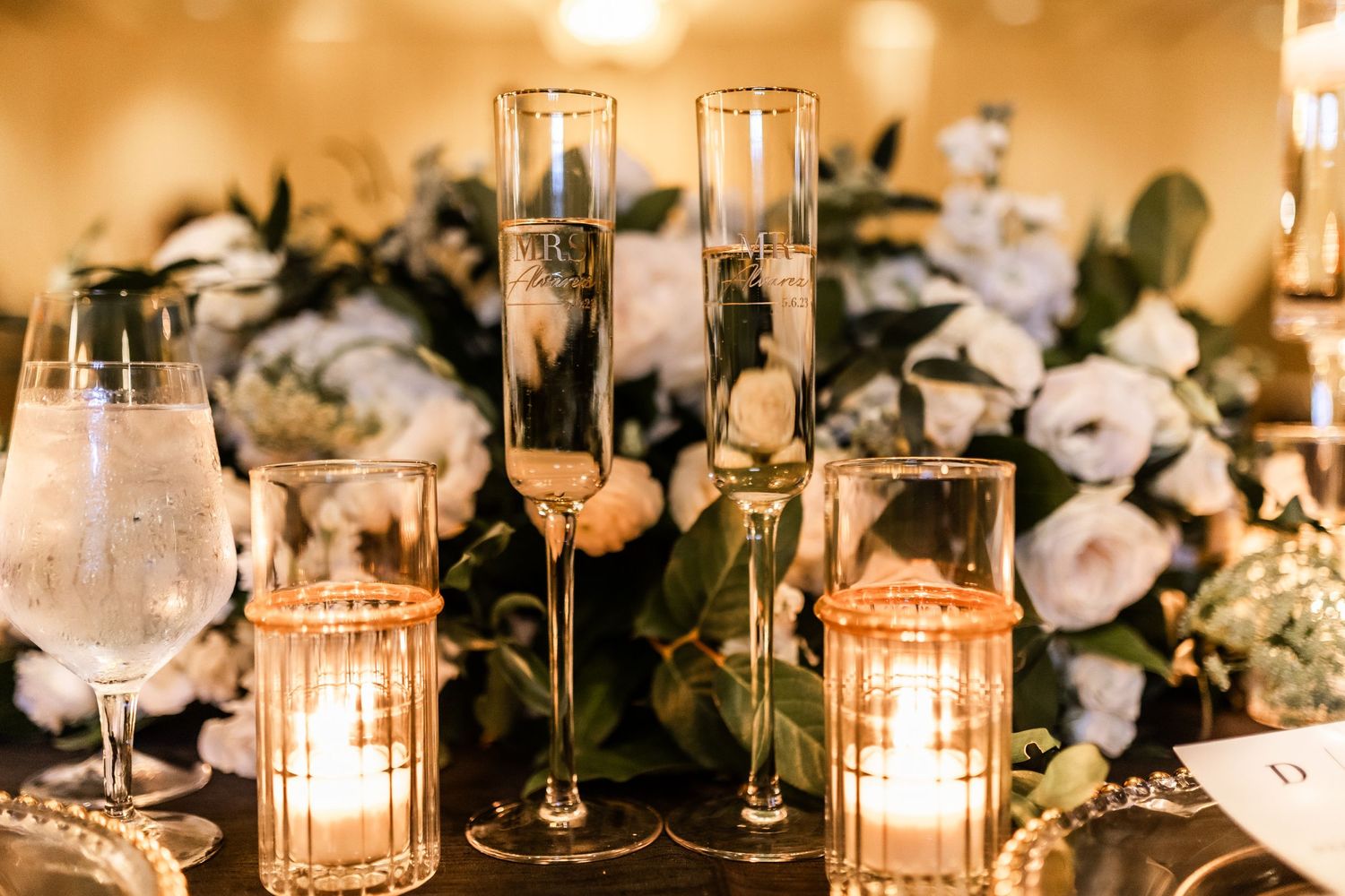 Romantic candlelit table settings with glowing votives and crystal glassware at an upscale event.
