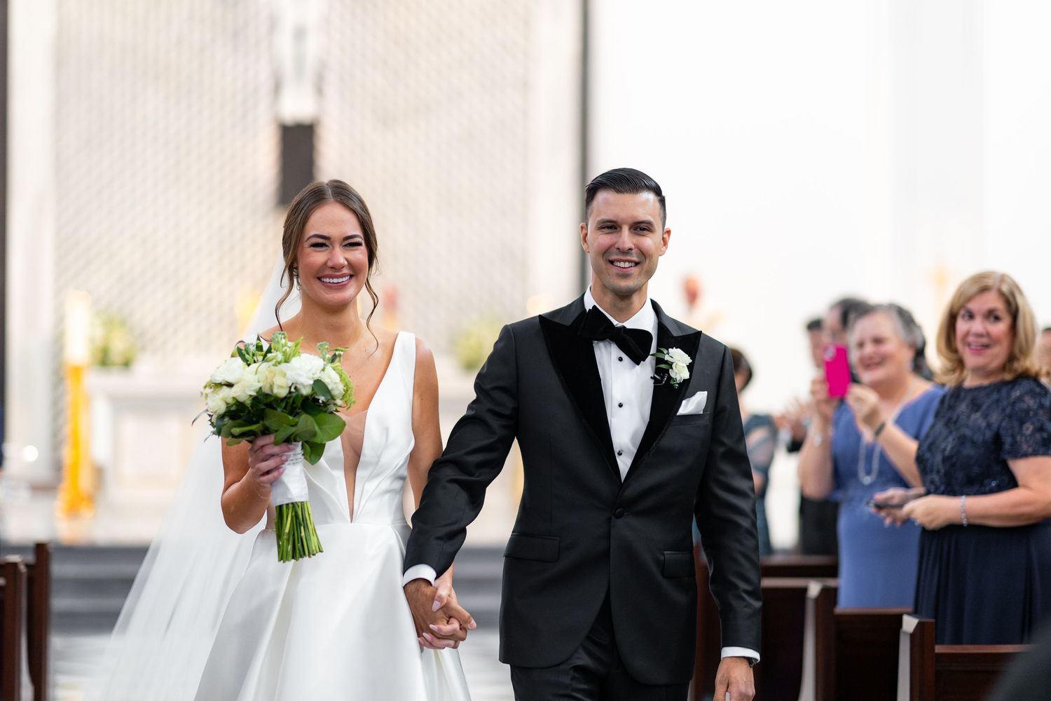 A wedding party processes down the aisle of a modern church after the ceremony.