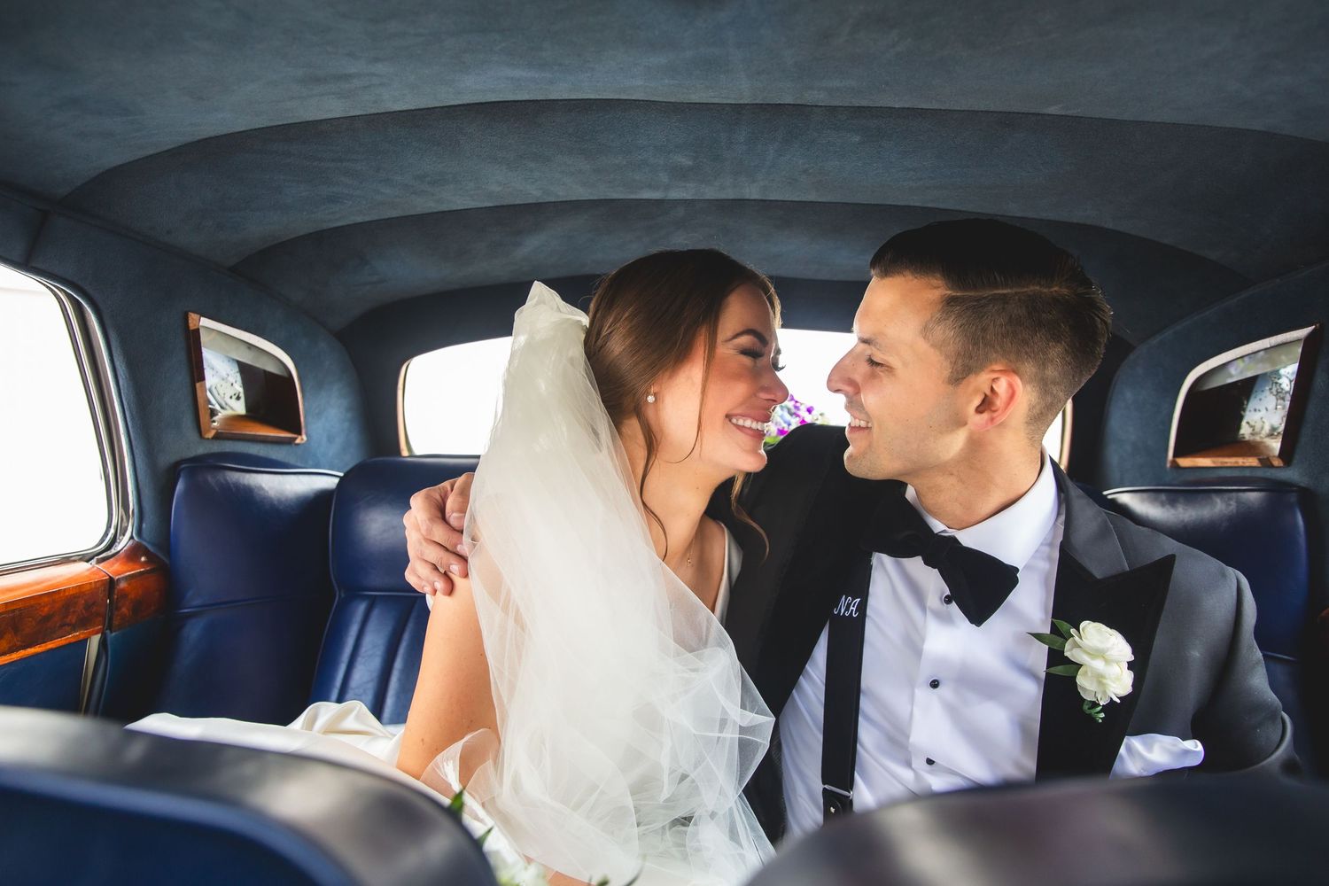 Romantic moments captured inside vintage car with blue leather seats.