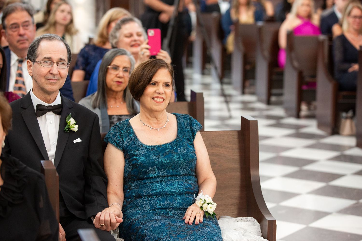 Wedding party members gather in formal attire with teal dresses and black tuxedos.