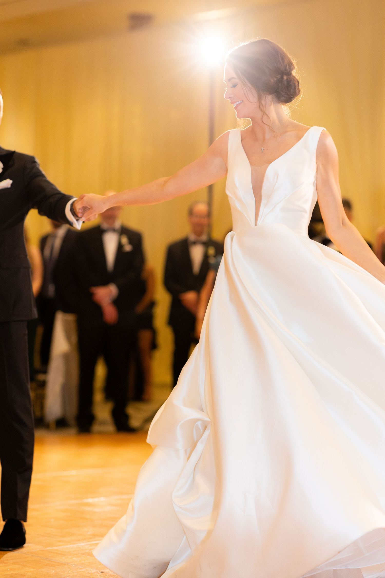 An elegant spin during a wedding first dance with flowing white gown in motion.