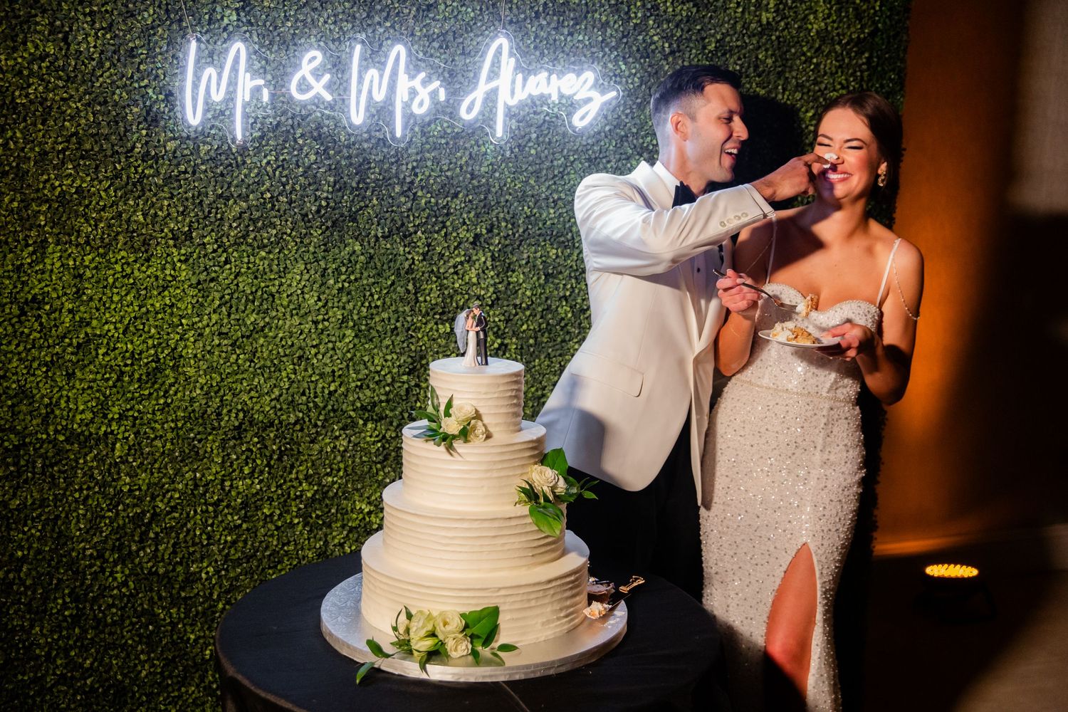 Playful cake-feeding moment between newlyweds at their reception.