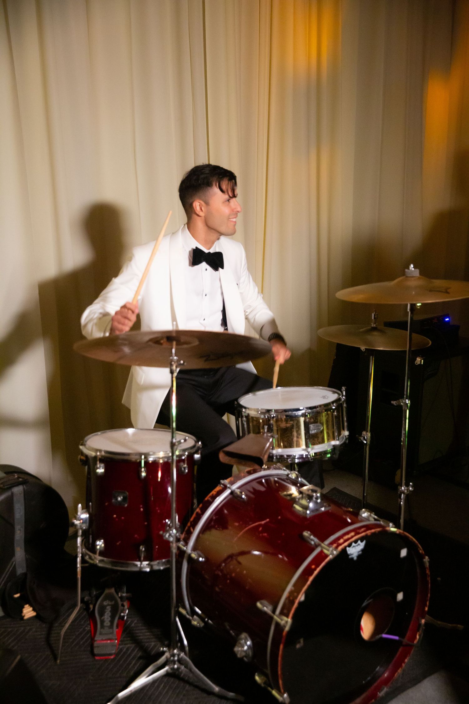 Close-up of drummer performing on red drum kit at formal event.