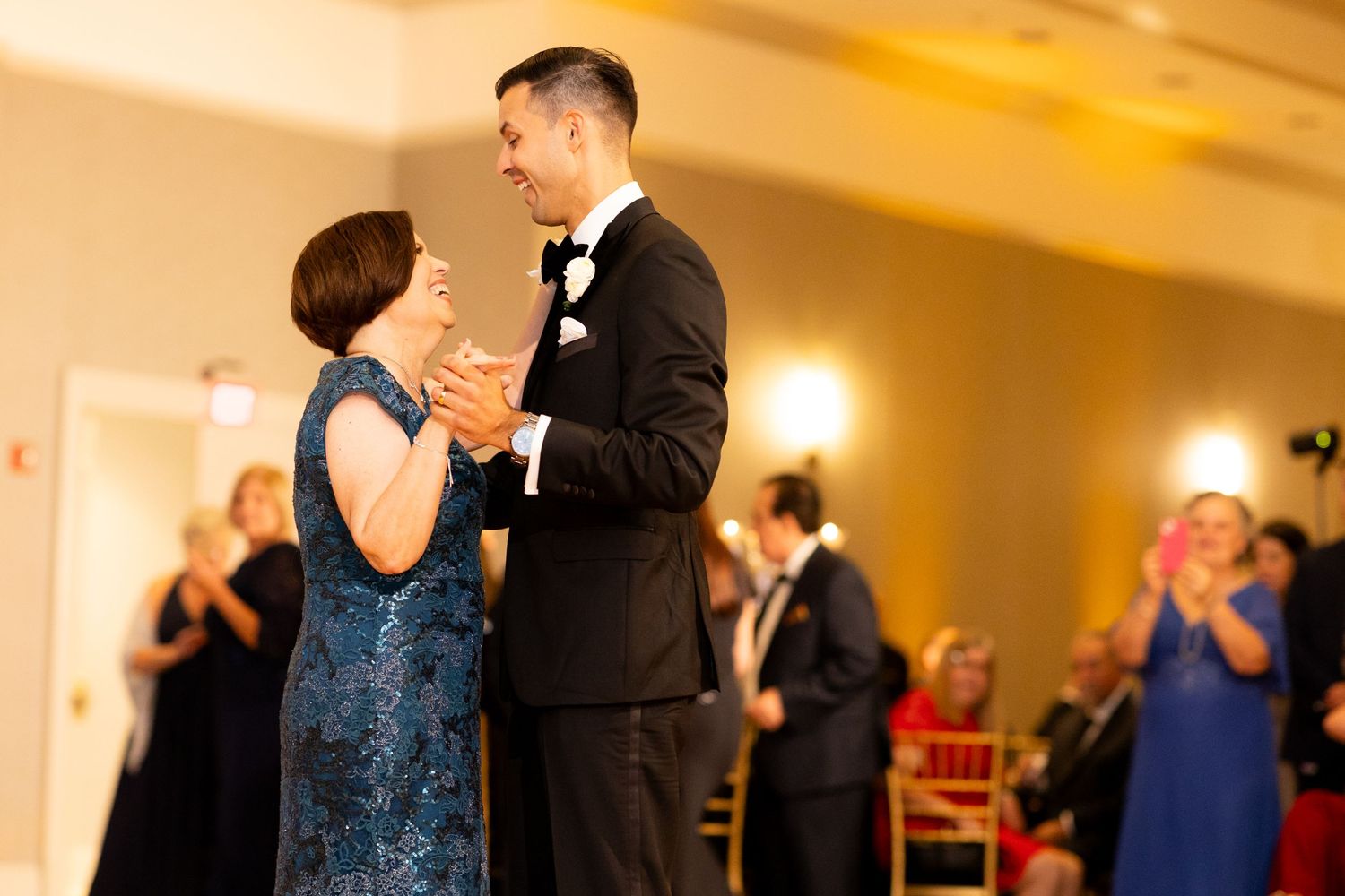 Couples dancing at formal wedding reception with elegant decor and mood lighting.
