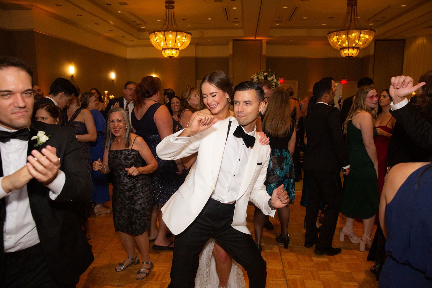 Formal event guests enjoying themselves on a dance floor under warm lighting.