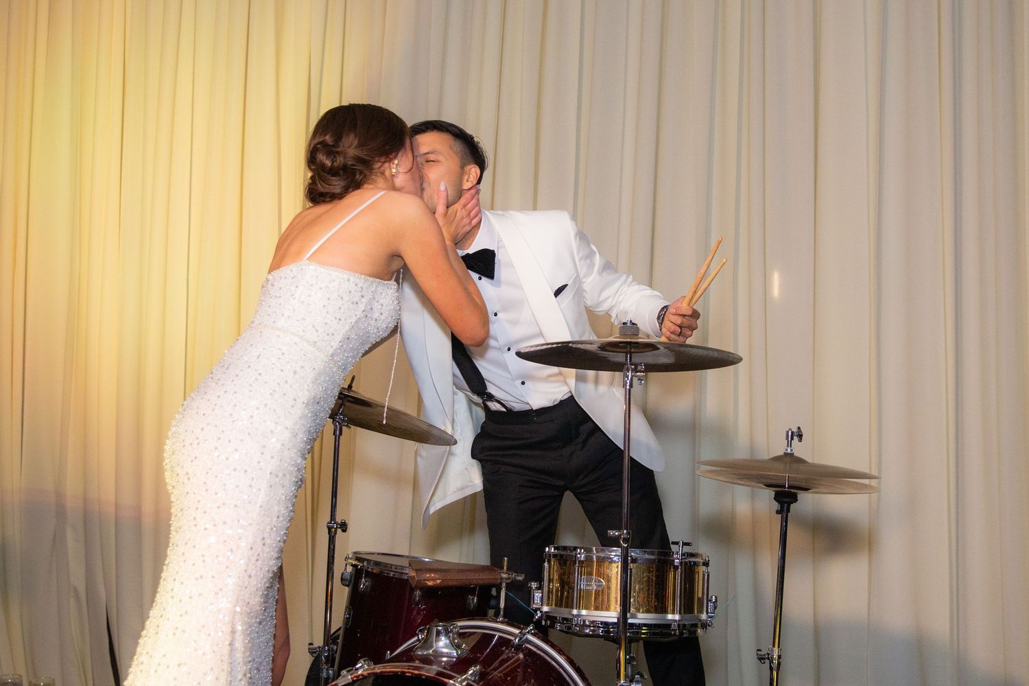 A wedding band performs live music in front of a white curtain backdrop.