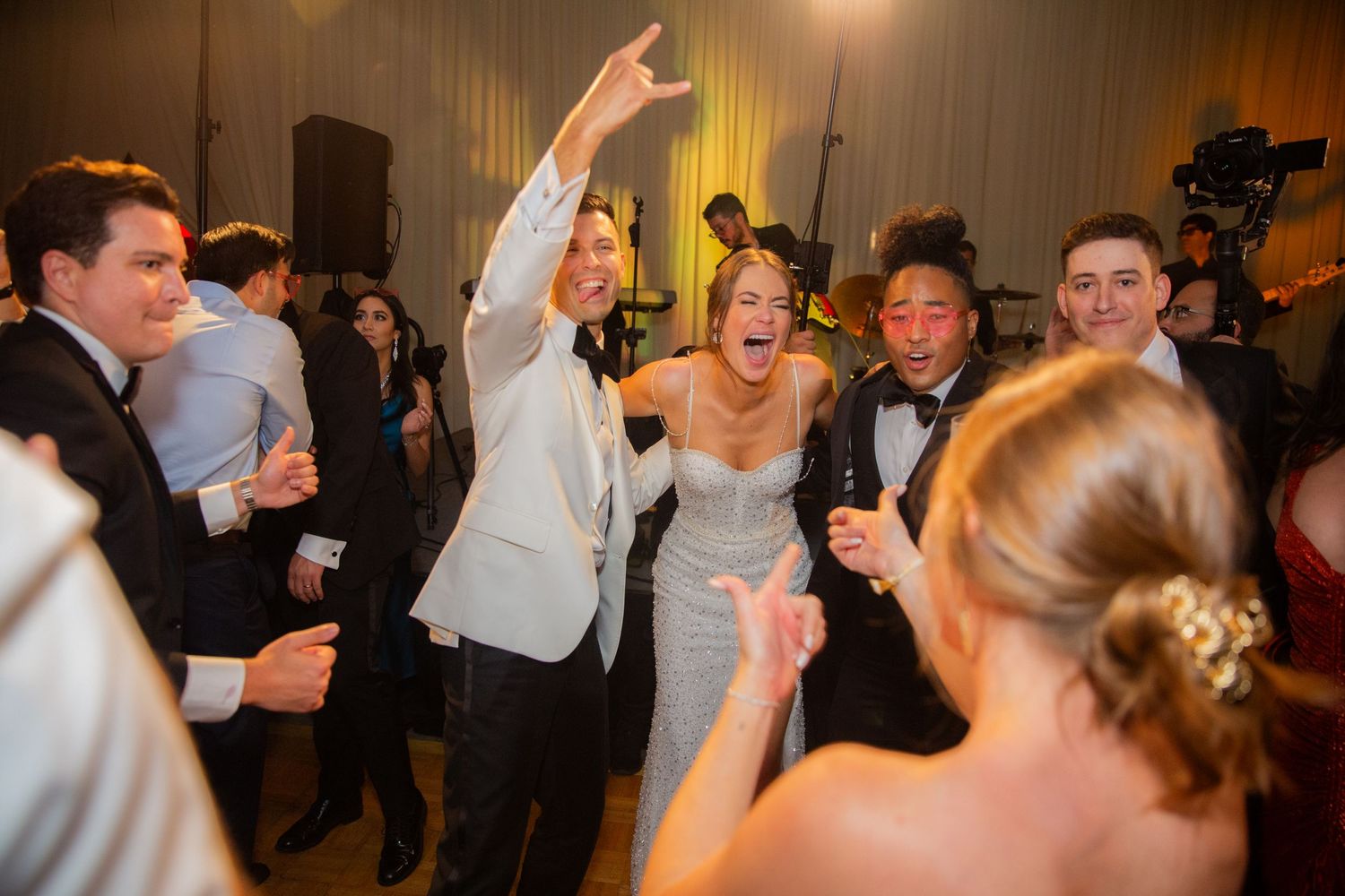 Wedding guests dancing and celebrating on a crowded dance floor.