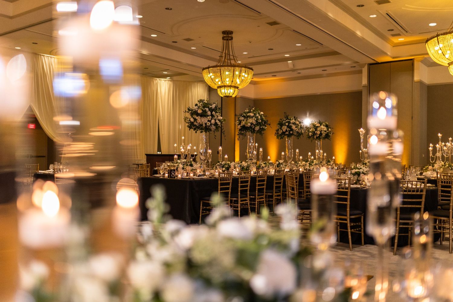 Elegant ballroom wedding reception with warm ambient lighting and crystal chandeliers.
