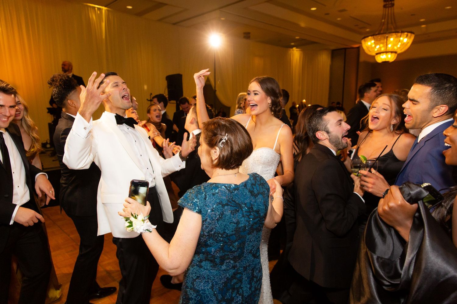 Festive ballroom scene with party guests dancing and celebrating at an evening event.