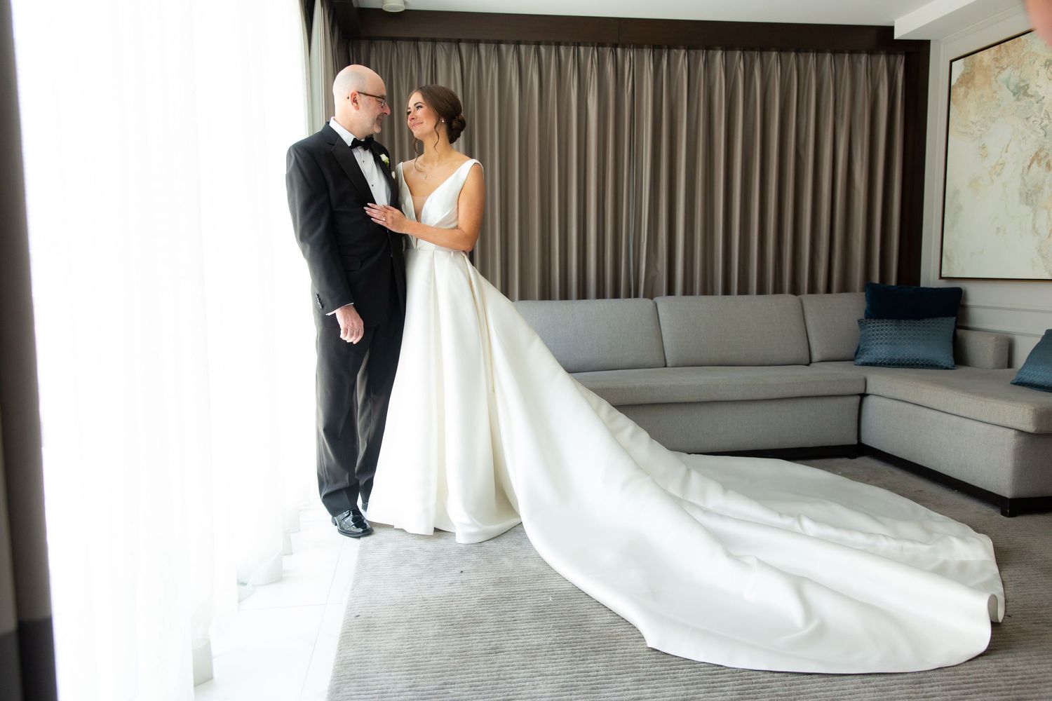 Wedding couple sharing intimate moment in modern room with grey couch.