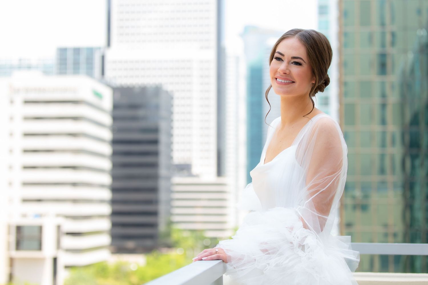 Wedding photography session on a sunny balcony with modern architecture and city views.