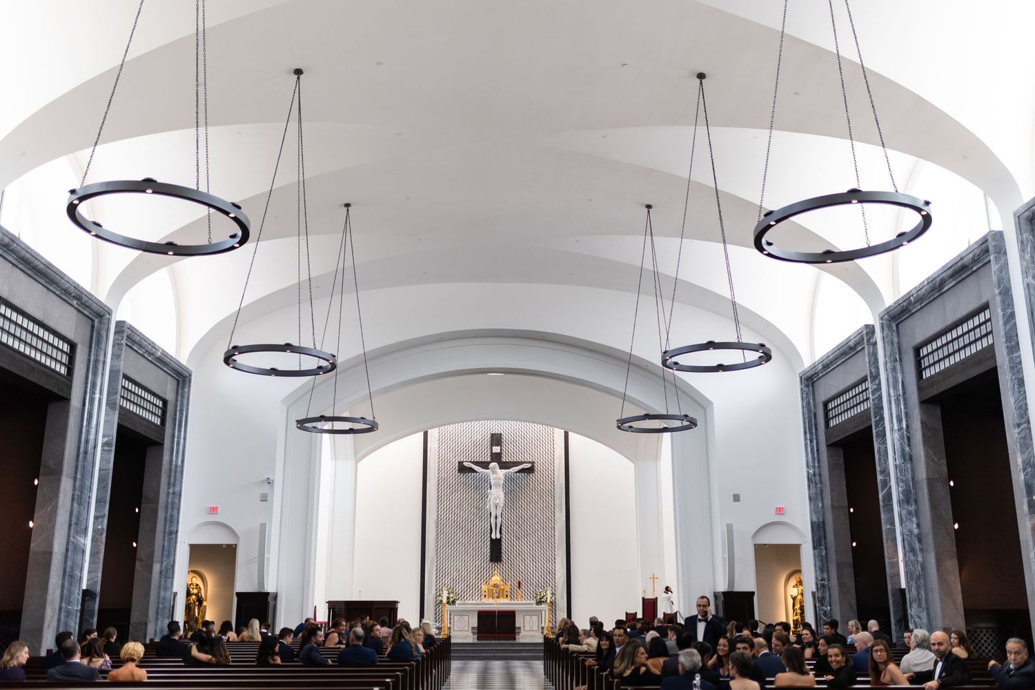 Modern event venue interior with circular pendant lights and vaulted white ceiling.