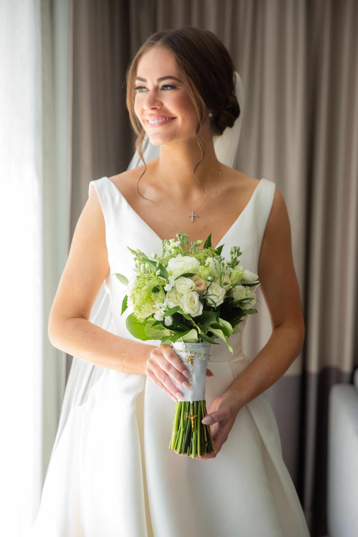 Elegant white bridal bouquet with fresh green and white flowers against a light background.