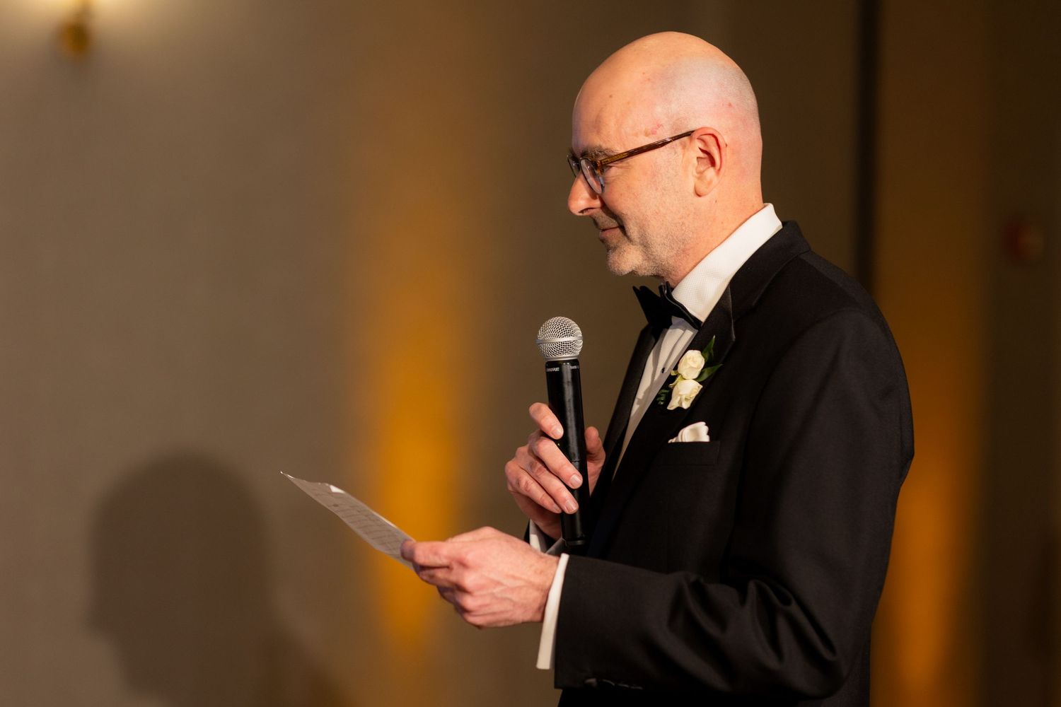 Wedding reception toasts being given at elegantly decorated head table.