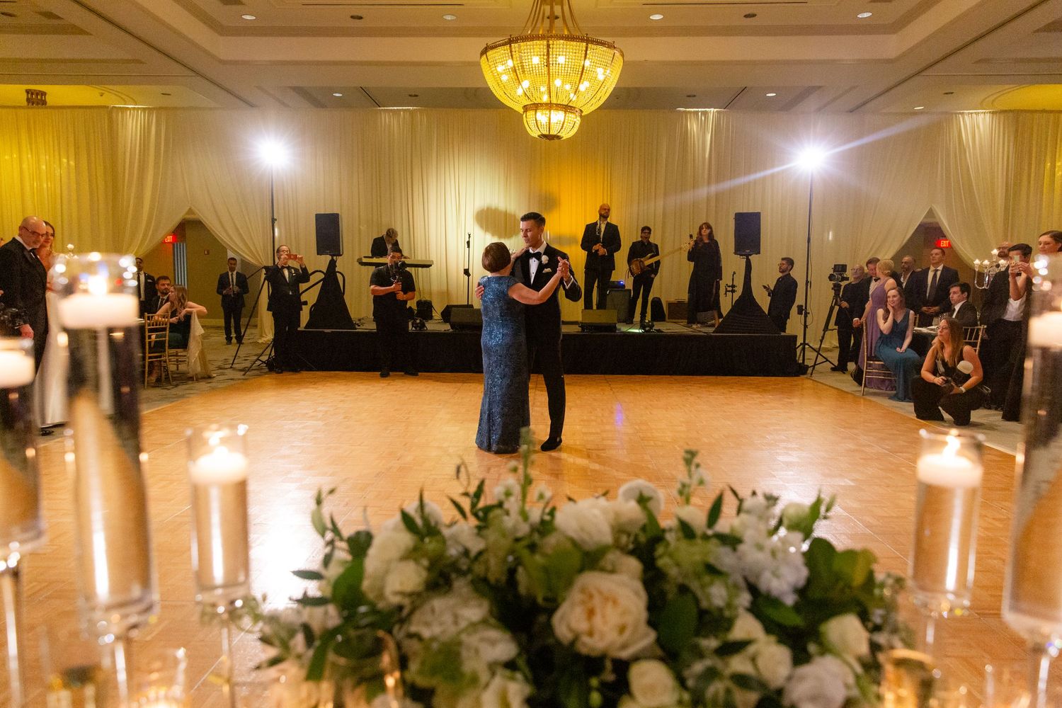 Wedding reception hall decorated with white floral arrangements and romantic lighting.