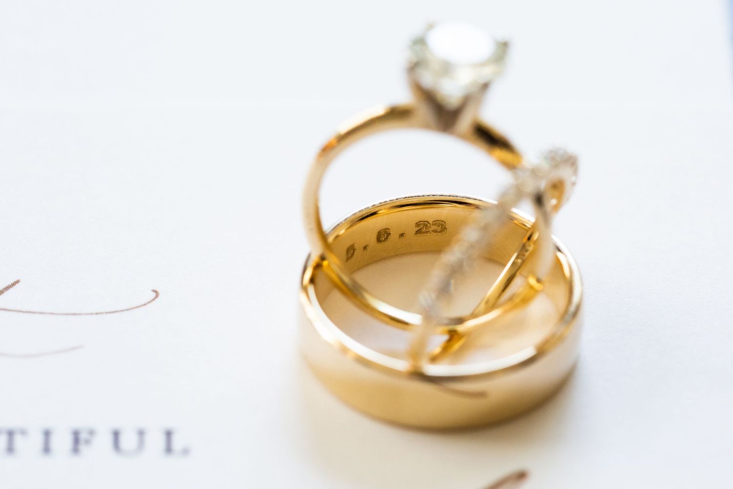 Gold wedding bands and engagement rings arranged artistically on white surface.