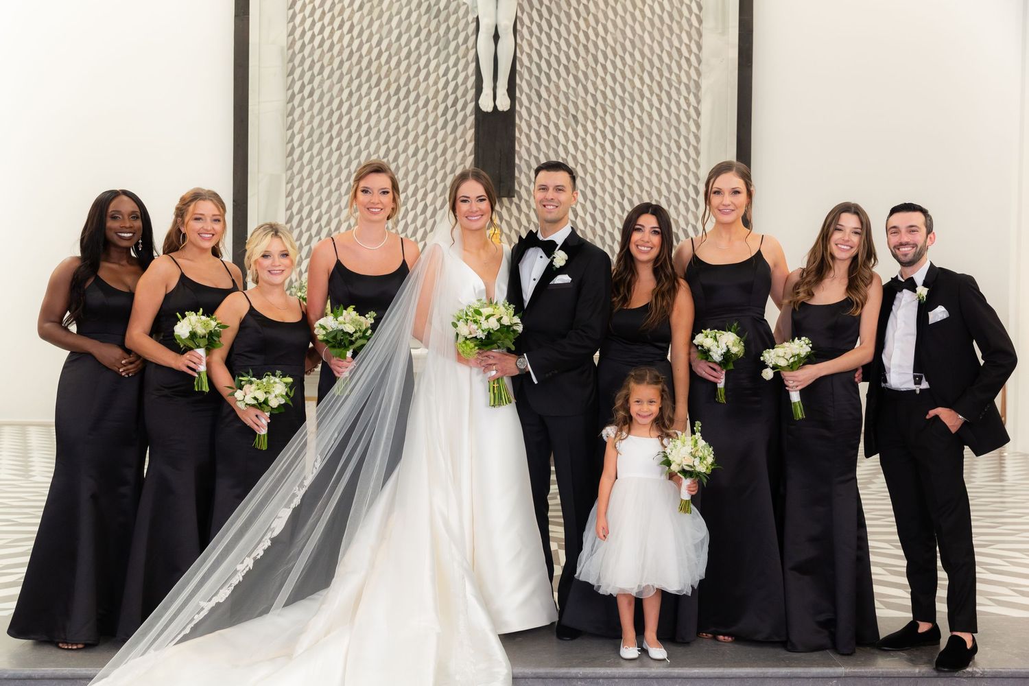 Wedding party wearing classic black and white attire posed for formal portrait.