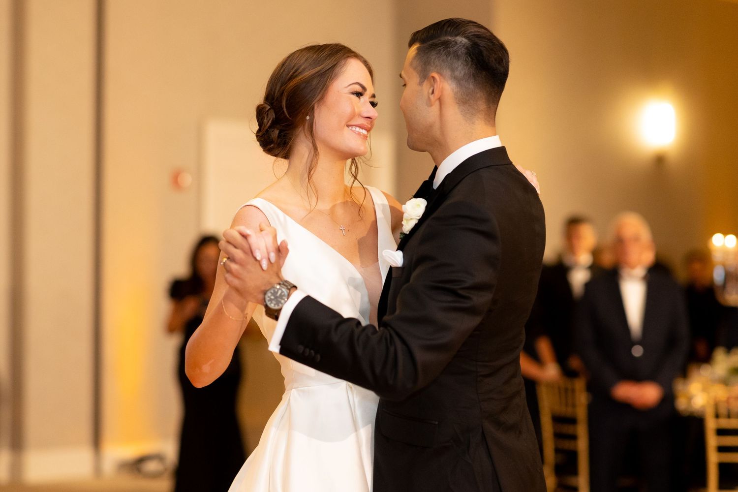 A romantic moment captured during a wedding first dance in a warmly lit reception venue.