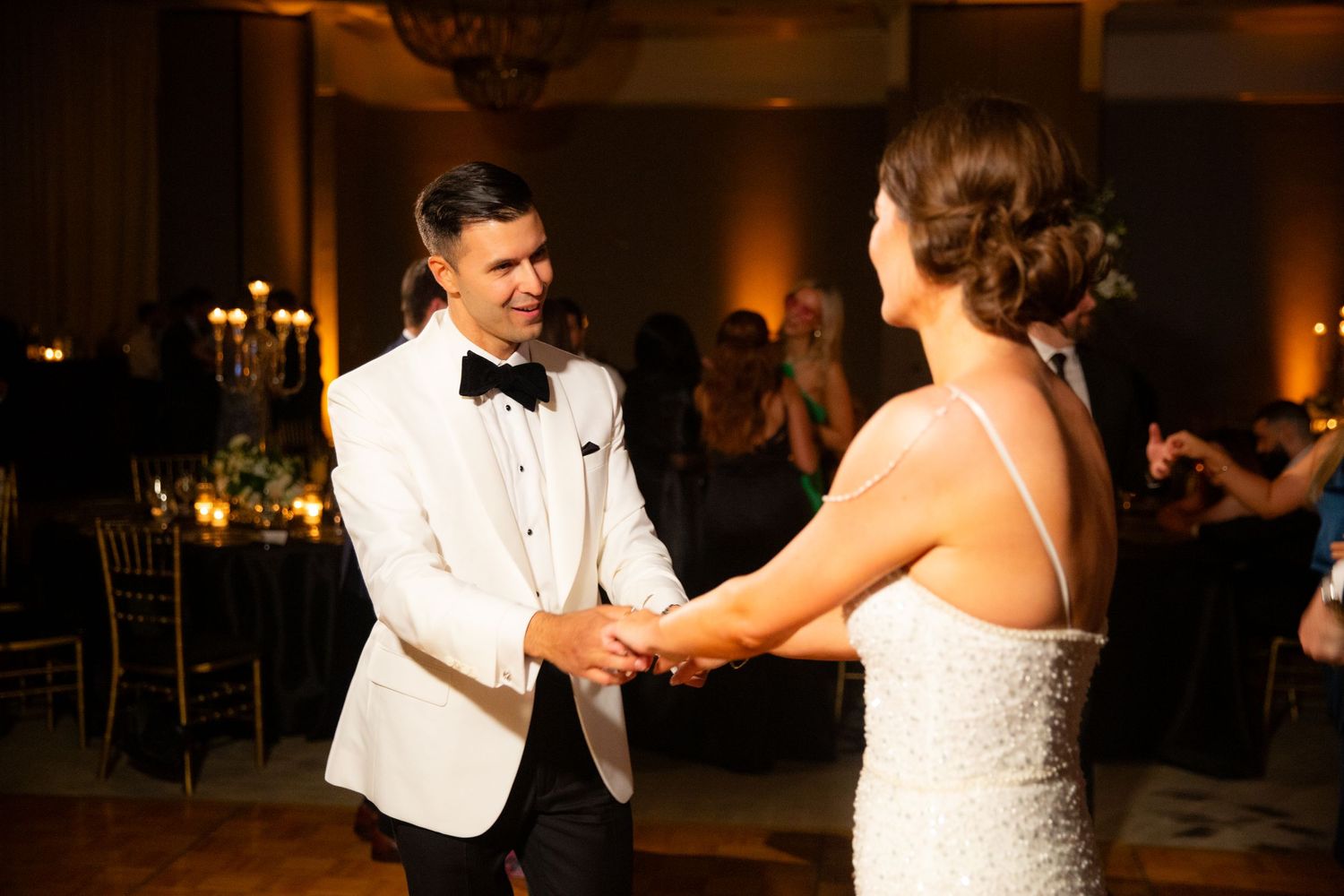 Couple dancing together at an elegant wedding reception with warm ambient lighting.