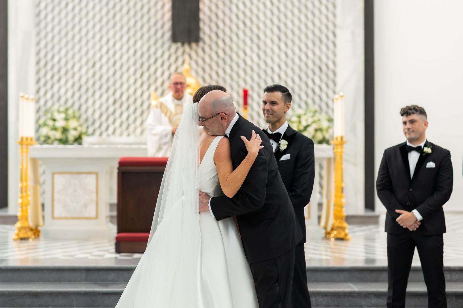 Wedding party members walking down church aisle during formal ceremony.