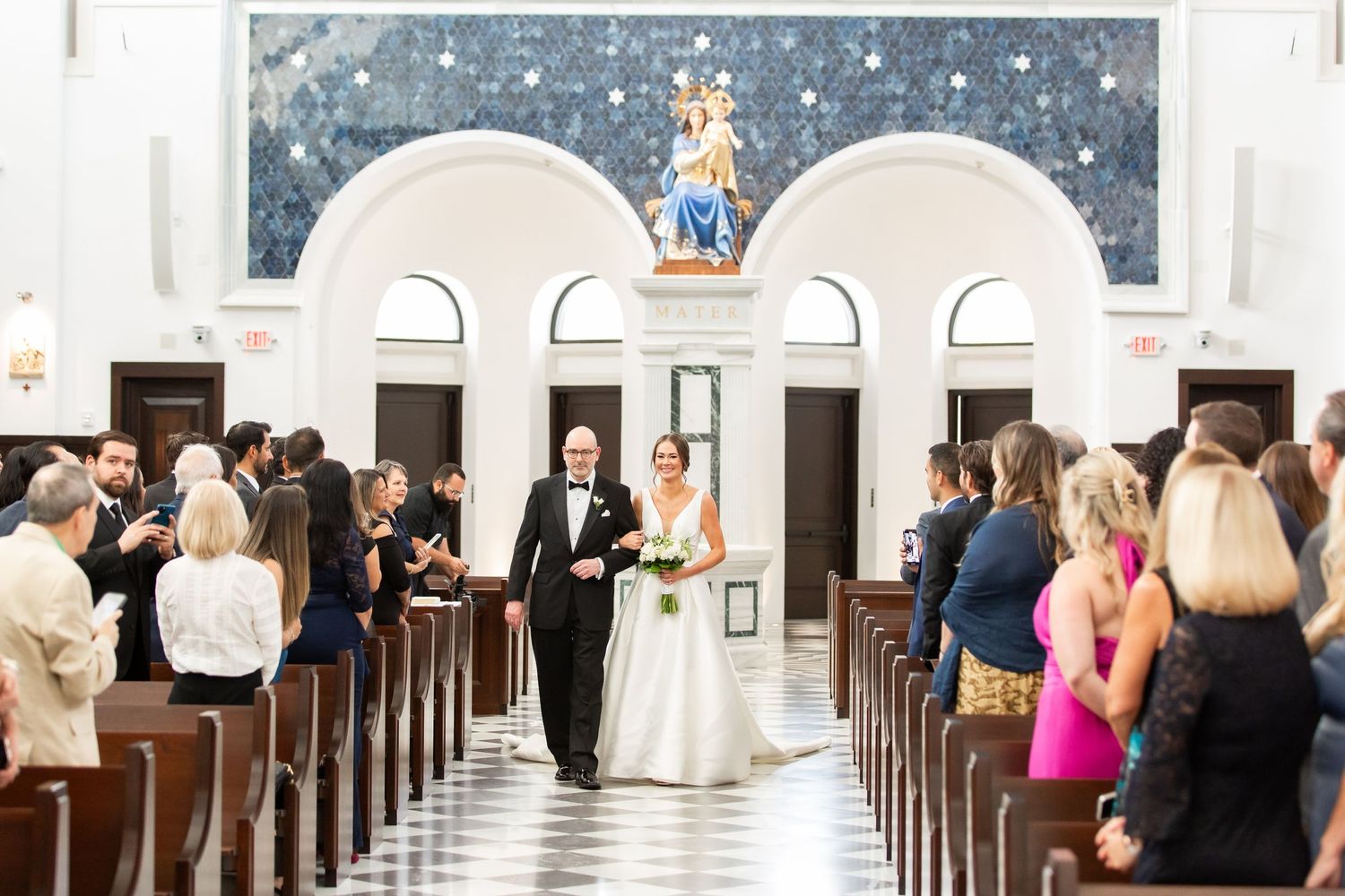 Church wedding ceremony showing guests seated in wooden pews under starry decorative ceiling.