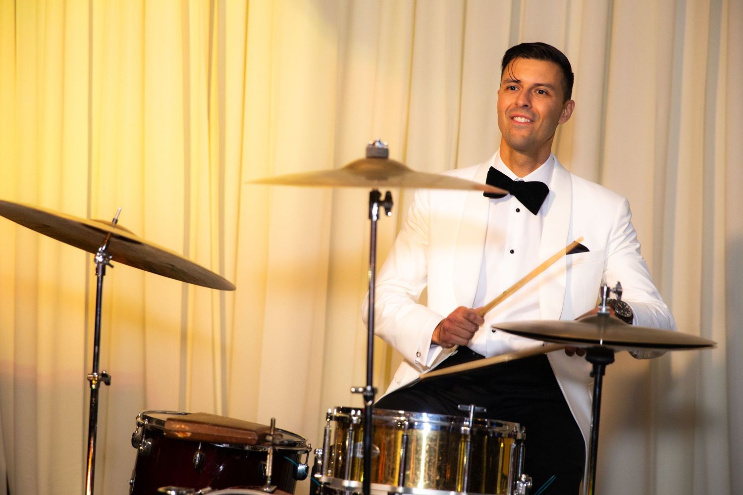 Drummer plays a red drum set during an elegant event performance.