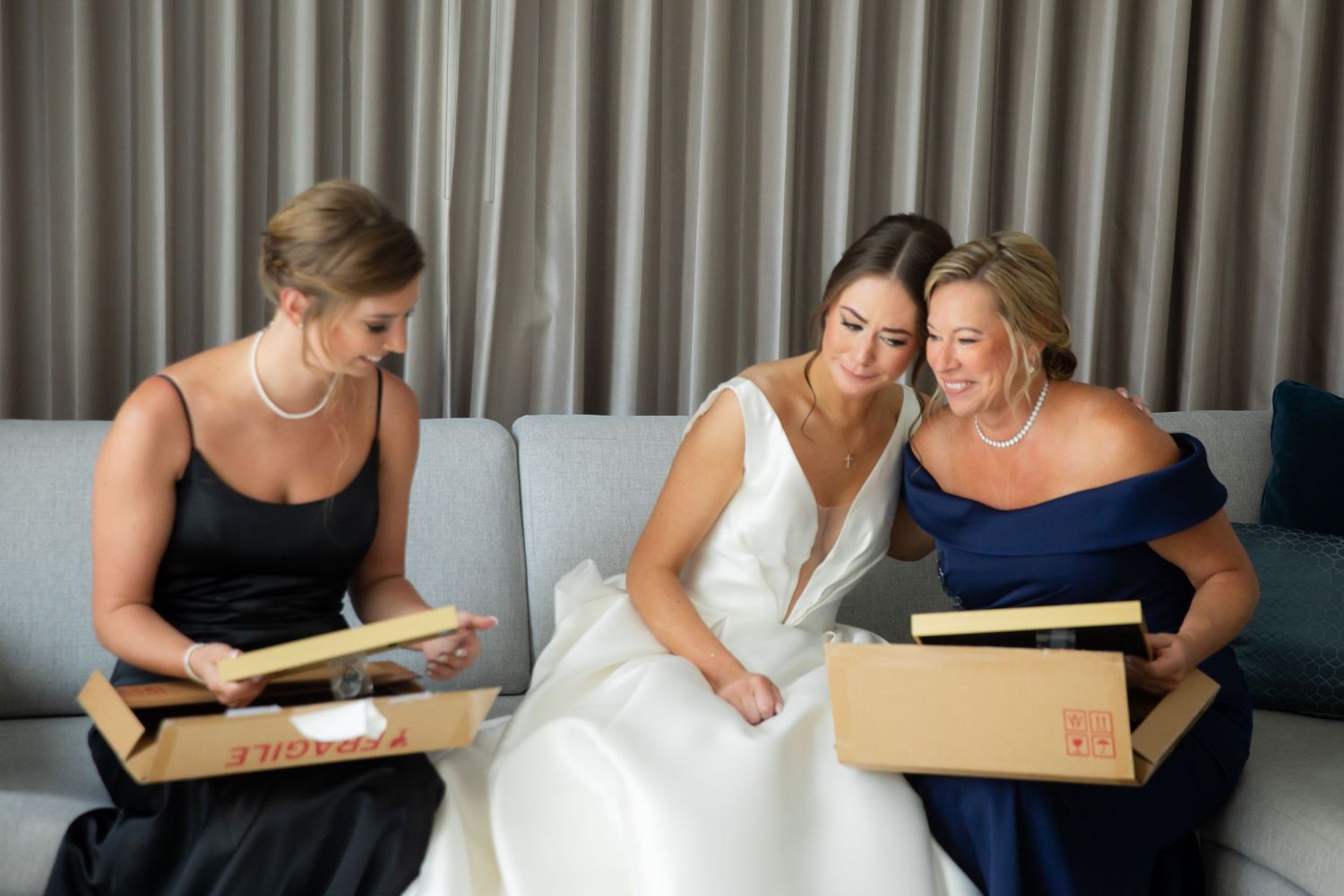 Bridesmaids in navy dresses gather around to look at a wedding photo album together.