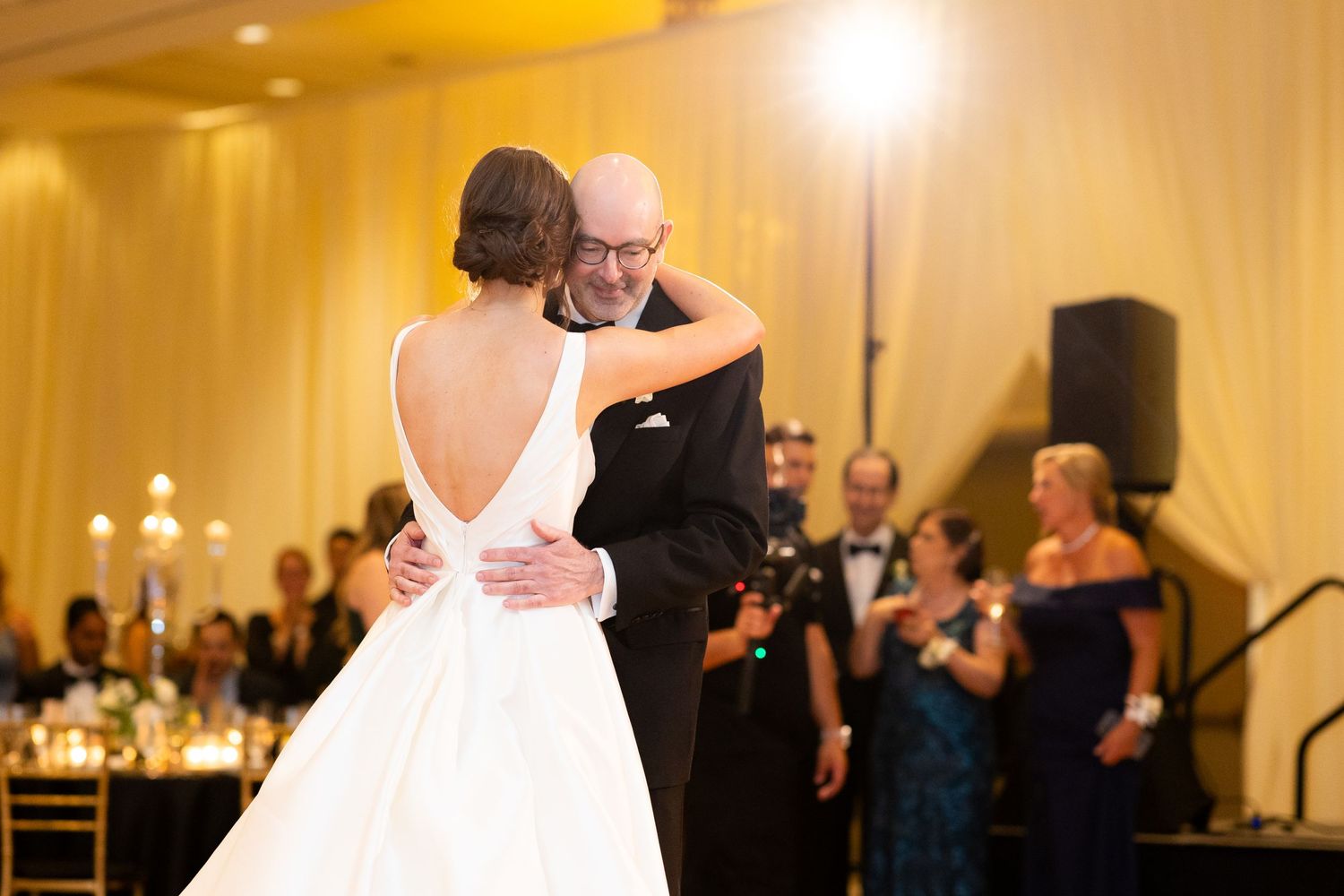 Elegant ballroom dance scene at a wedding reception with warm lighting and formal attire.